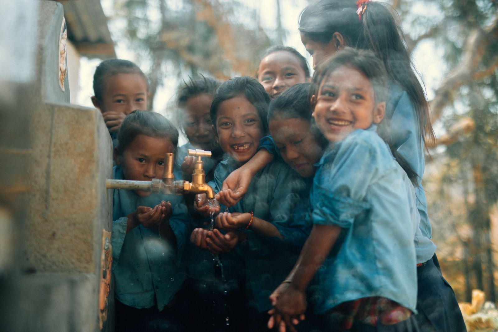 Children laughing together at a water tap
